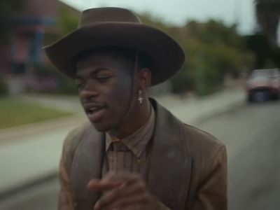 Lil Nas X is wearing a cowboy dress in the picture.